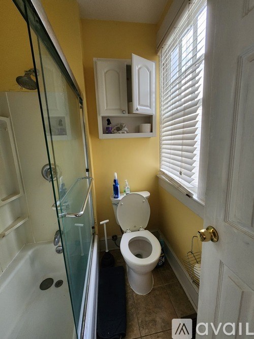 A bathroom with yellow walls has a toilet, a bathtub, and a cabinet.