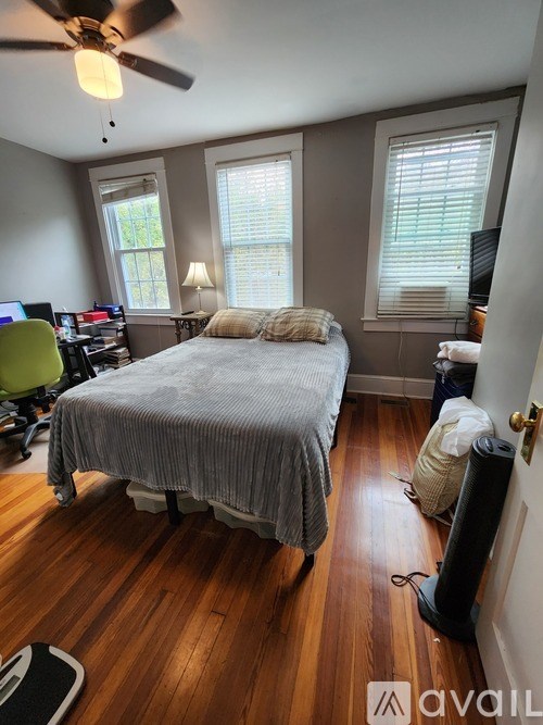 A bedroom with a bed, desk, and ceiling fan.