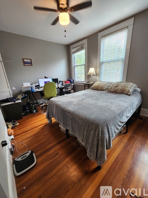 A bedroom with a bed, desk, and ceiling fan.