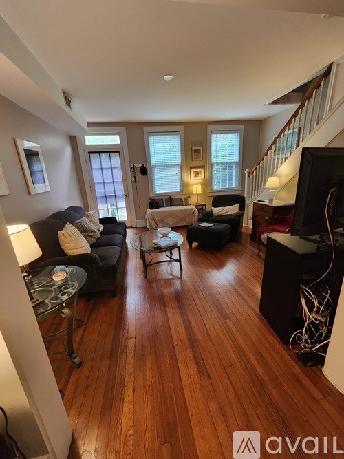 A living room with a wooden floor and a staircase.