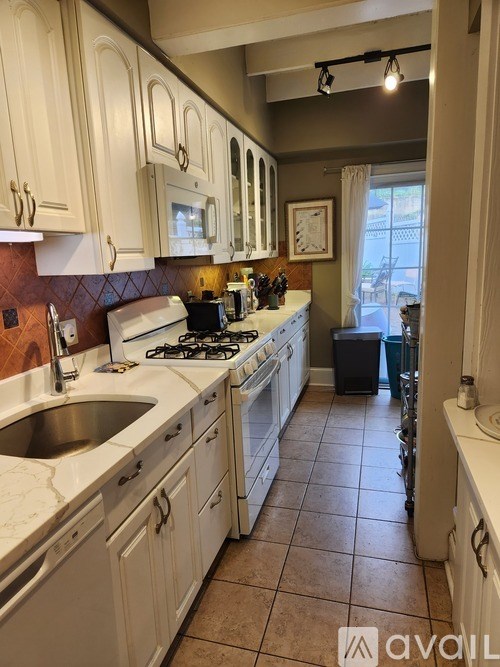 A kitchen with white cabinets and a tiled floor.