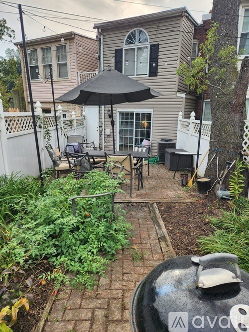 A backyard with a table and chairs under an umbrella.