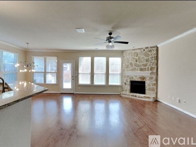 A spacious living room with a stone fireplace and hardwood floors.