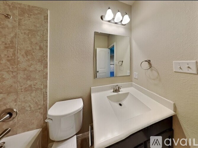 A bathroom with a toilet, sink, and mirror.