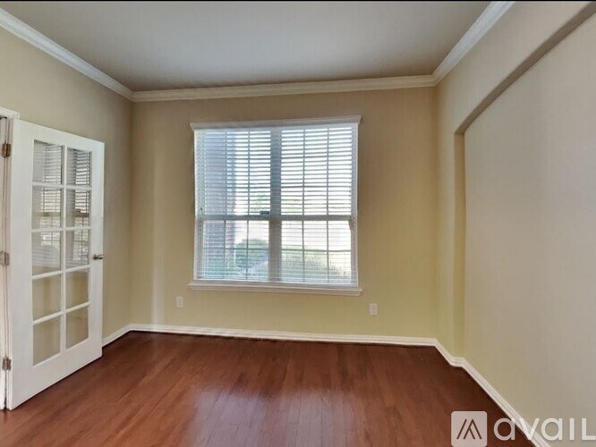 A room with a wooden floor and a window with blinds.