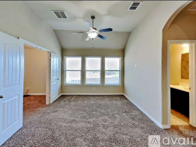 A spacious room with a ceiling fan and carpeted floor.