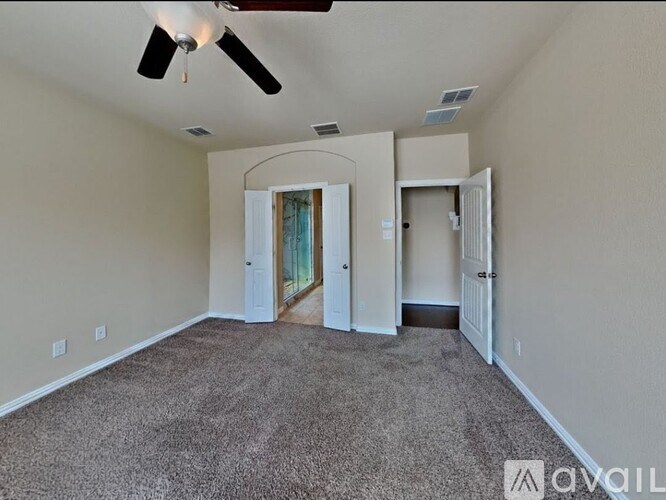 A room with a carpeted floor and a ceiling fan.