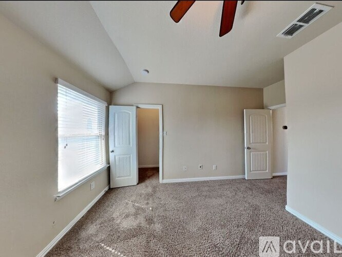 A room with a carpeted floor and a ceiling fan.