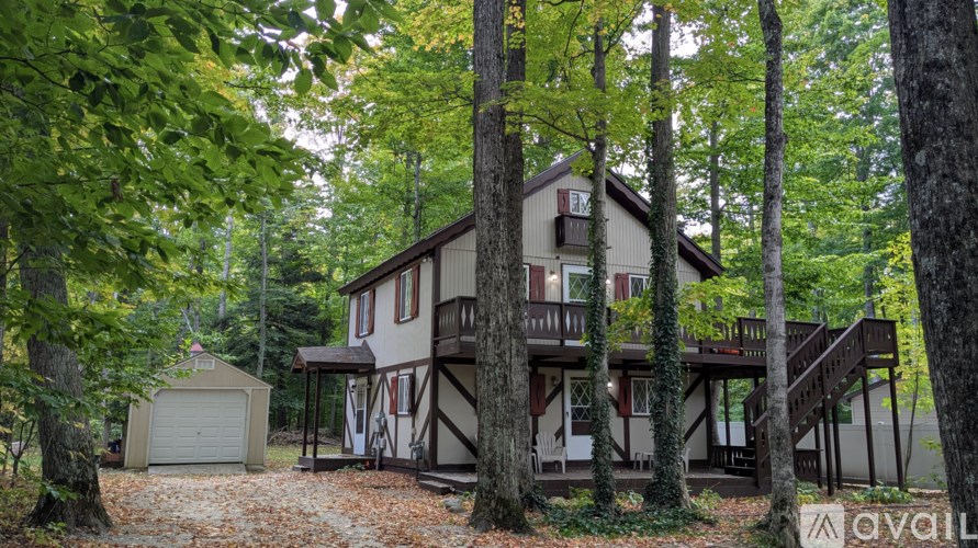 A house with a balcony is surrounded by trees.