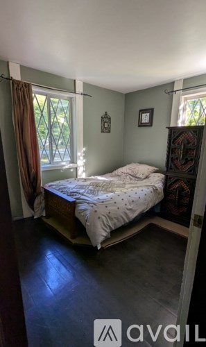 A bedroom with a bed, a window with curtains, and a wooden cabinet.