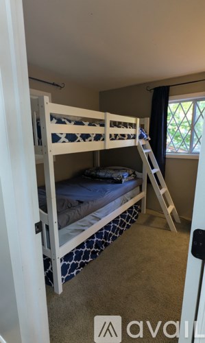 A white bunk bed with a ladder is in a room with carpeted floor.