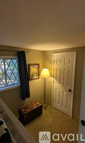 A lamp stands in a corner of a room with a door and a window.