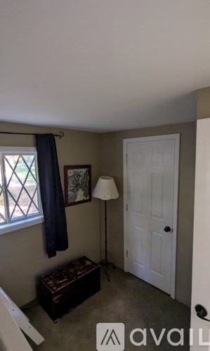 A room with a window, a door, a lamp, and a coat hanging on the wall.