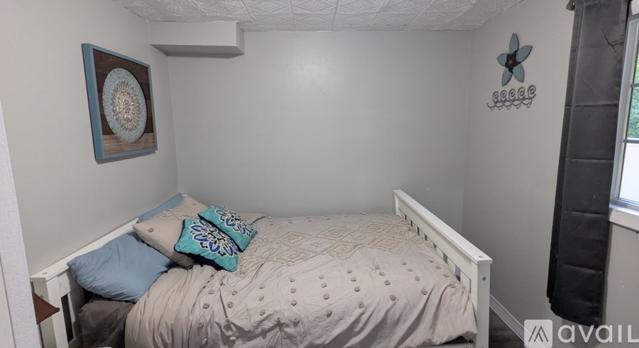 A bedroom with a bed, pillows, and a wall decoration.