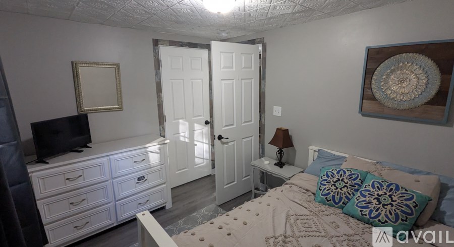 A bedroom with a bed, dresser, and a television.
