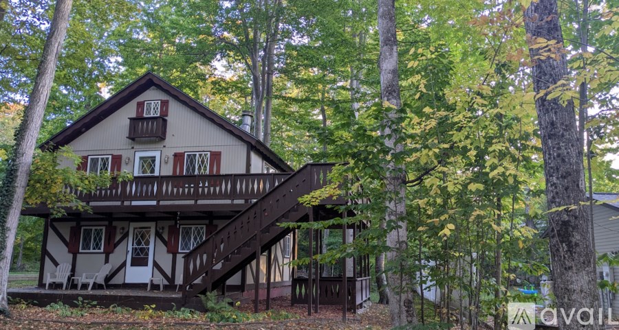 A house with a balcony is surrounded by trees.