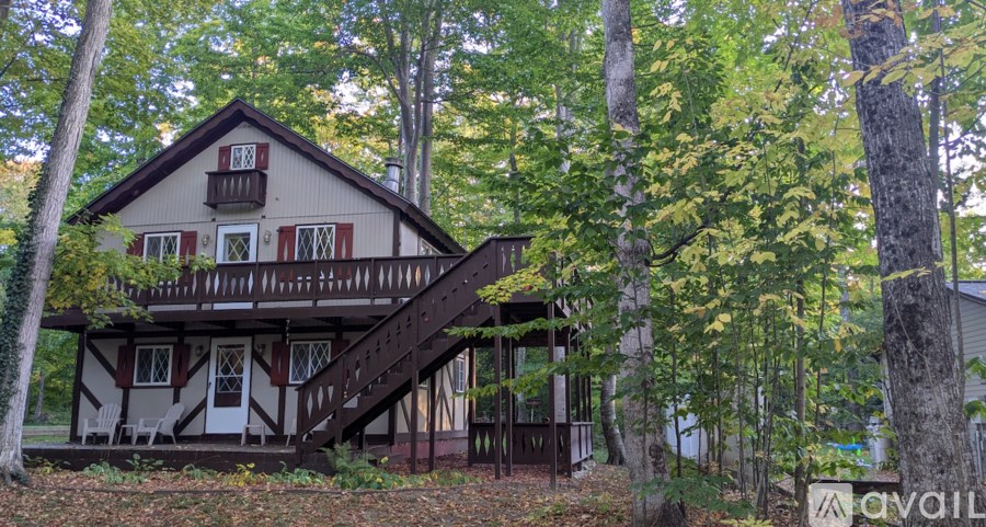 A house with a balcony and a tree in front of it.