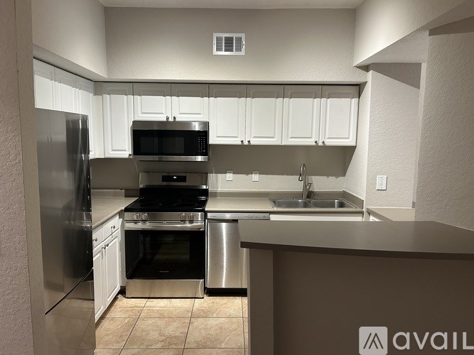 A kitchen with a refrigerator, microwave, oven, and sink.