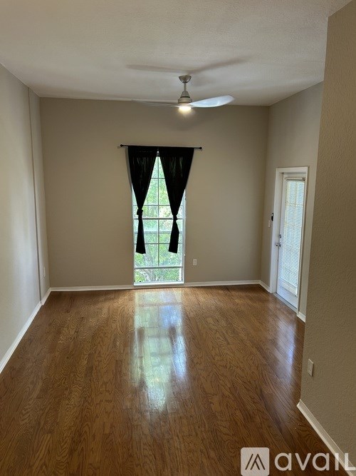 A room with wooden flooring and a window with black curtains.
