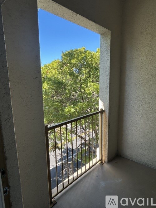 A balcony with a metal railing and a view of trees and a road.