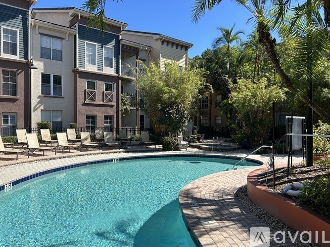 A pool surrounded by chairs and trees in front of apartment buildings.