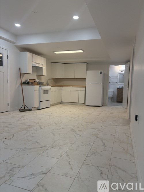 A kitchen with white cabinets and appliances, and a marble floor.
