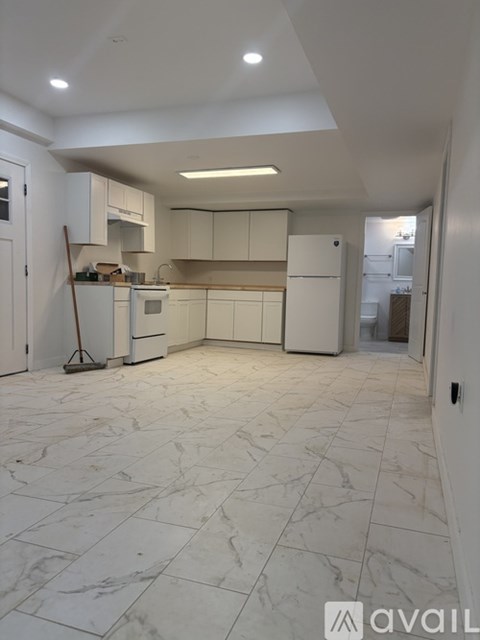 A kitchen with white cabinets and appliances, and a marble floor.