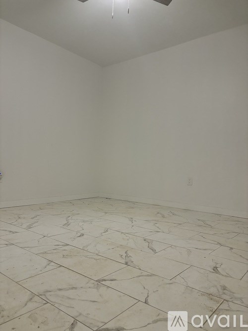 A room with a marble floor and a ceiling fan.