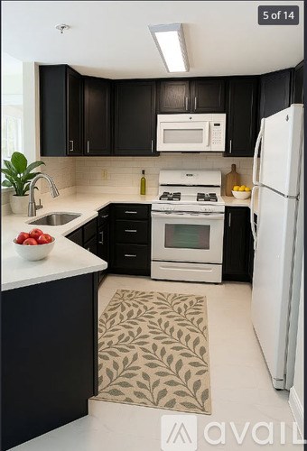 A kitchen with black cabinets and white appliances.