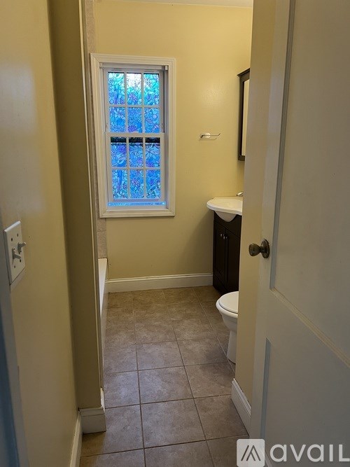 A bathroom with a toilet, sink, and a window.
