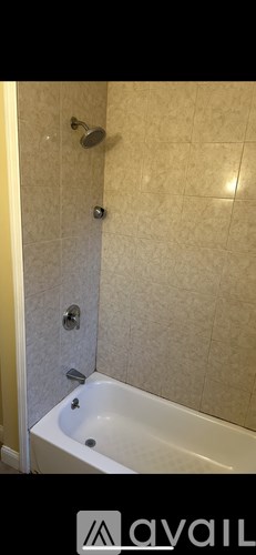 A white bathtub with a shower head above it.