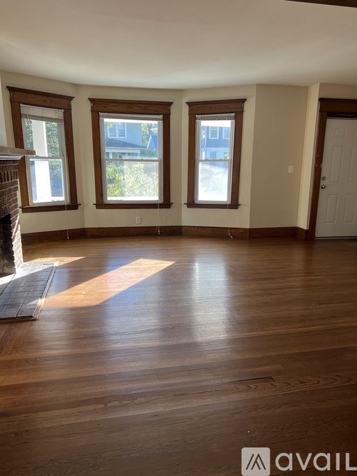 A room with wooden floors and three windows.