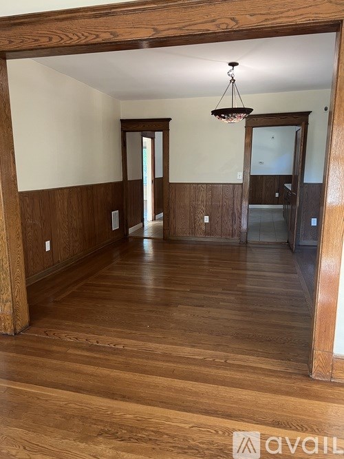 A room with wooden floors and a chandelier hanging from the ceiling.