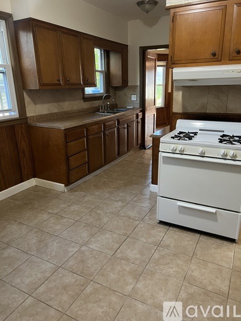 A kitchen with a white stove and wooden cabinets.