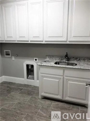 A kitchen with white cabinets and a granite countertop.