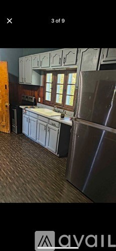 A kitchen with wooden flooring and a stainless steel refrigerator.