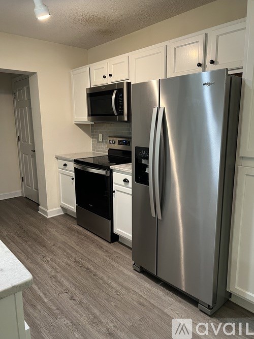 A kitchen with a stainless steel refrigerator and black countertops.