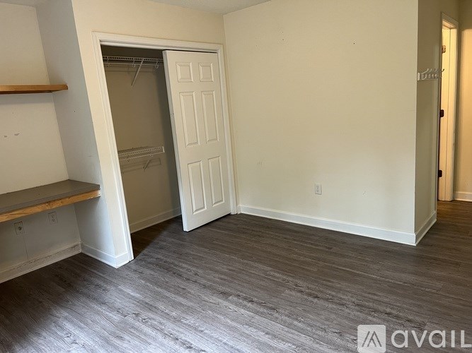 A room with a white door and a wooden shelf.