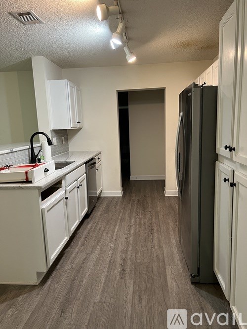 A kitchen with white cabinets and a grey fridge.