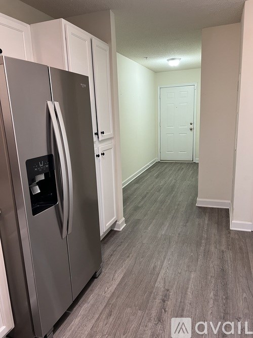 A stainless steel refrigerator in a kitchen with white cabinets.