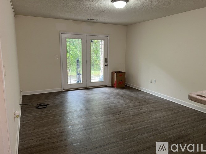 A room with a wooden floor and a door leading outside.