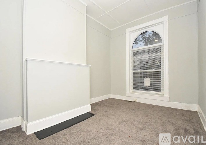 A room with a window and a white wall.