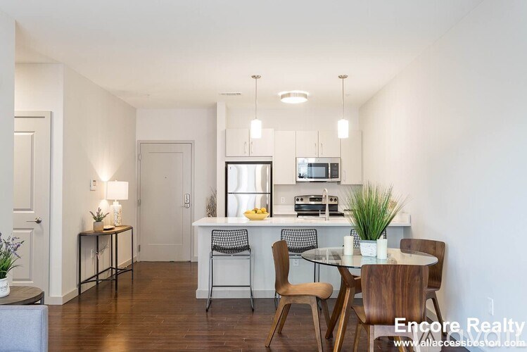 A dining room with a table set for two and a kitchen area in the background.
