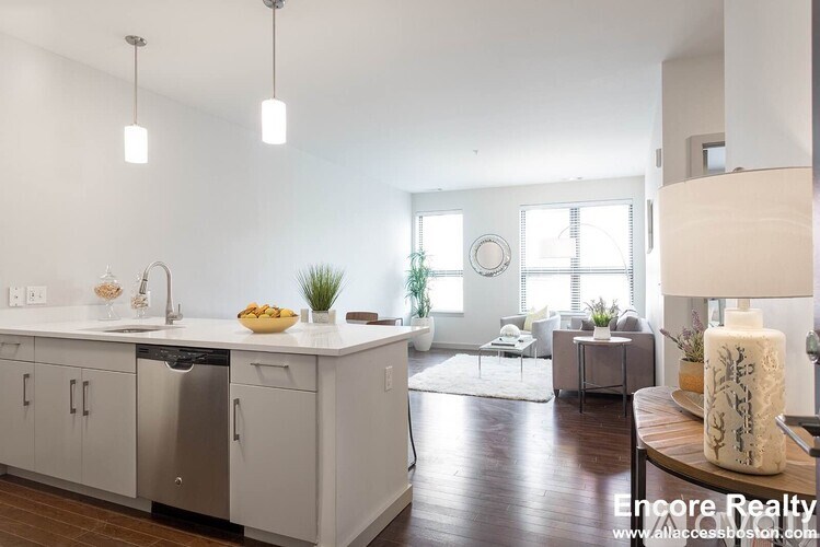 A modern kitchen with white cabinets and a wooden floor.