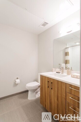 A bathroom with a toilet, sink, and mirror.