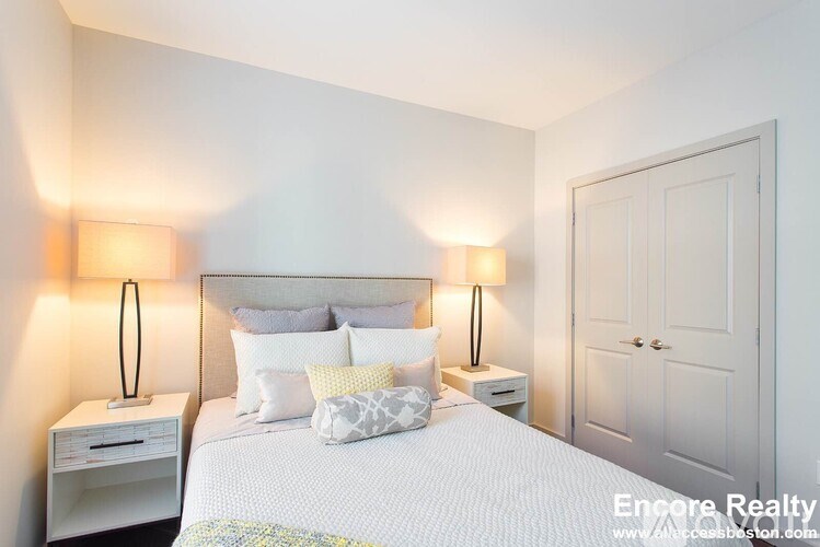 A bedroom with a bed, nightstands, and a door.