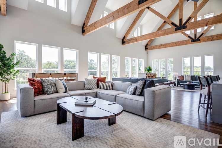 A spacious living room with a large grey sofa, a coffee table, and a wooden ceiling.