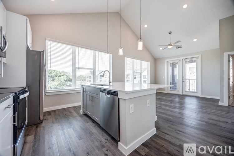 A modern kitchen with stainless steel appliances and a wooden floor.