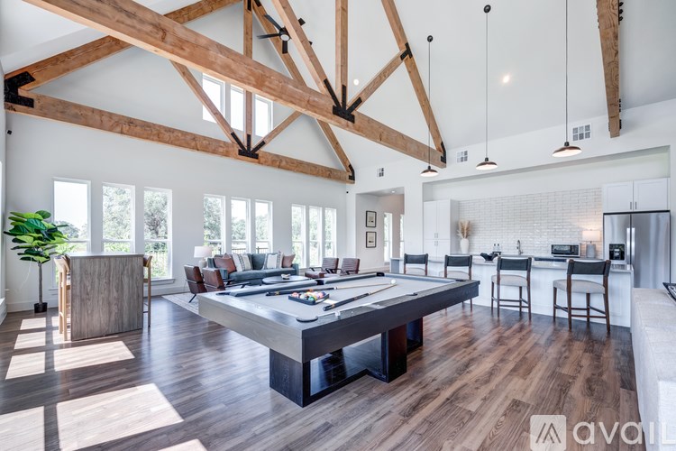 A large open living room with a pool table and a kitchen area in the background.