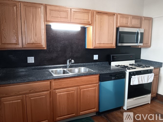 A kitchen with wooden cabinets and black countertops.